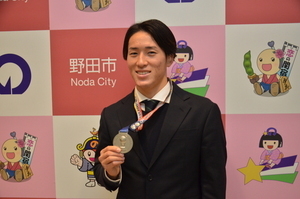 バックパネルの前で銀メダルを見せる瀧澤選手