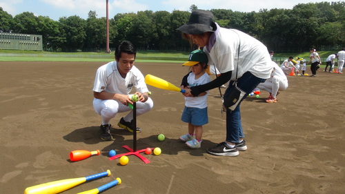 立てた棒の上に乗せたボールを打つ子どもの写真