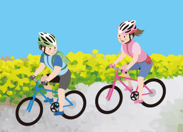 ヘルメットを着用しサイクリングロードを自転車で走る男女