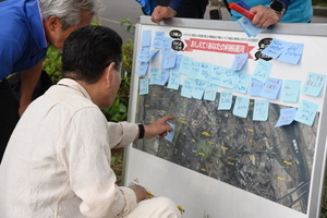 利根運河へのコメントがついたパネルを読む市長